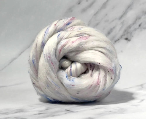 White Polwarth combed top with blue and pink viscose nepps wound into a ball.